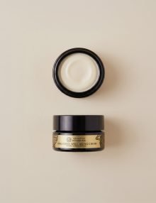 Open cosmetic jar labeled Bakuchiol Well-Aging Cream with cream visible inside on a beige background